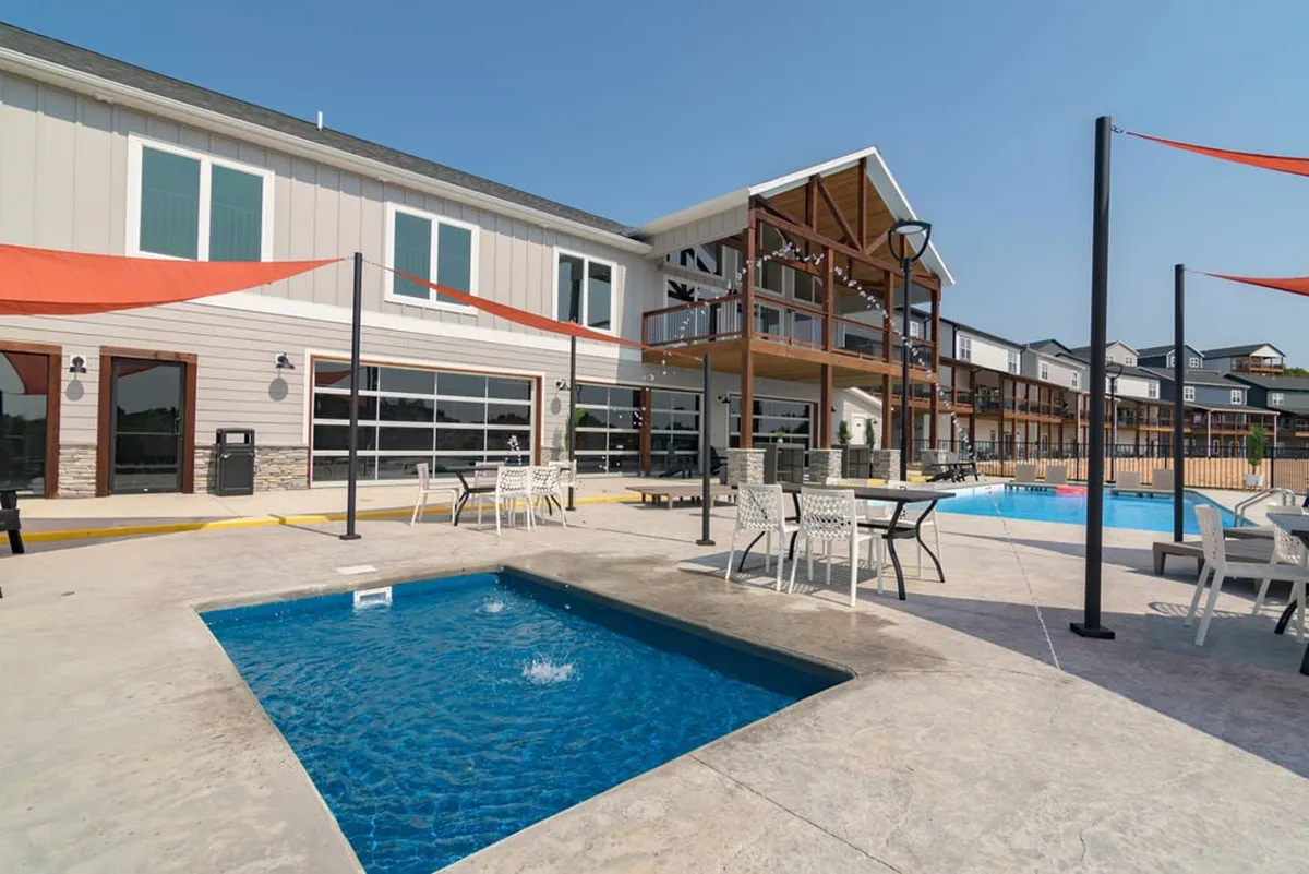 A modern outdoor space featuring a swimming pool, jacuzzi, and a stylish seating area. The area is set up for both relaxation and socializing, making it ideal for celebrating after a round of golf. Modern architecture and sunset lighting add an upscale feel.