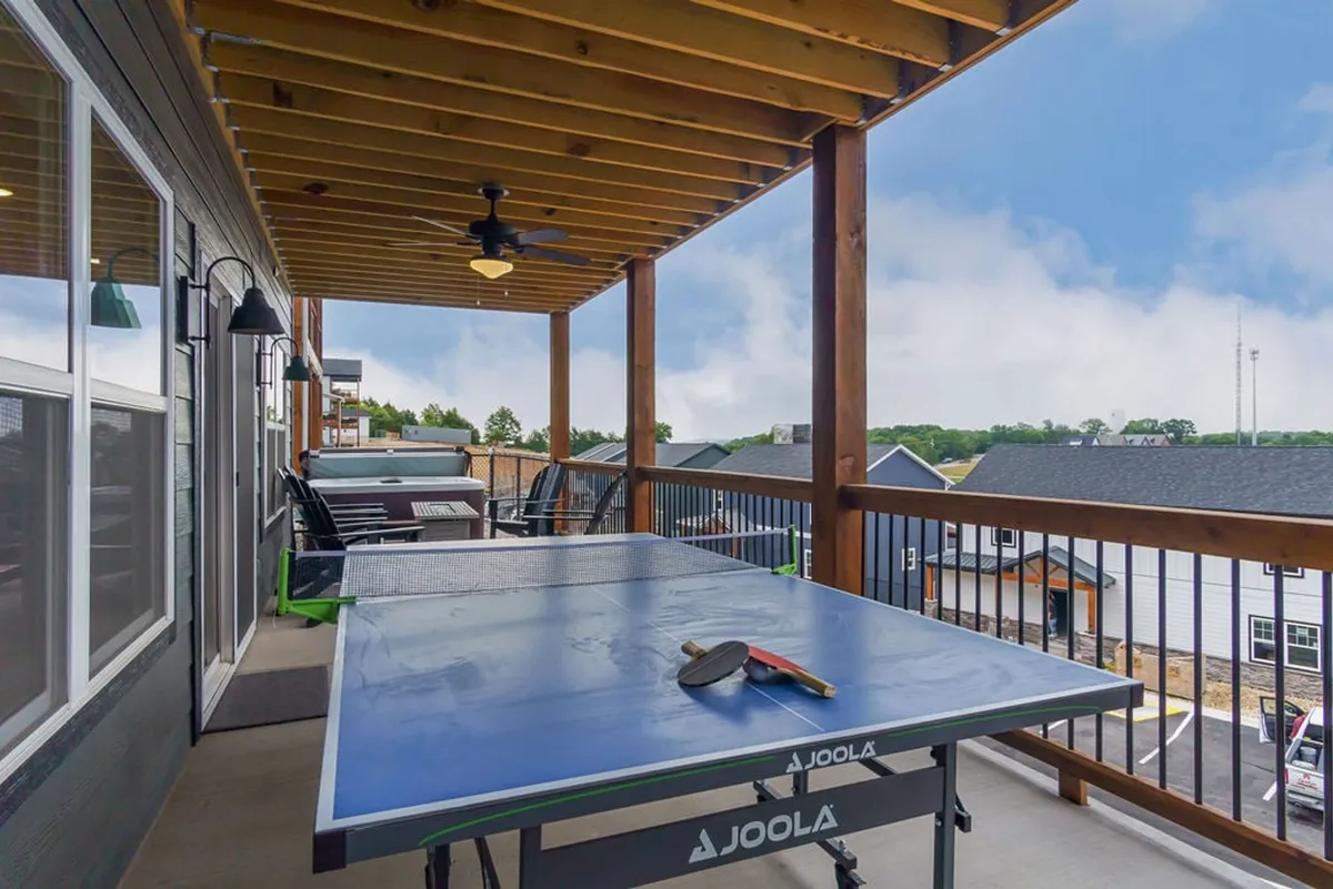 This exterior shot features an outdoor ping pong table under a wooden ceiling, surrounded by comfortable seating and open views. The relaxed, playful atmosphere is enhanced by hints of sunset light and plenty of space for group activities.