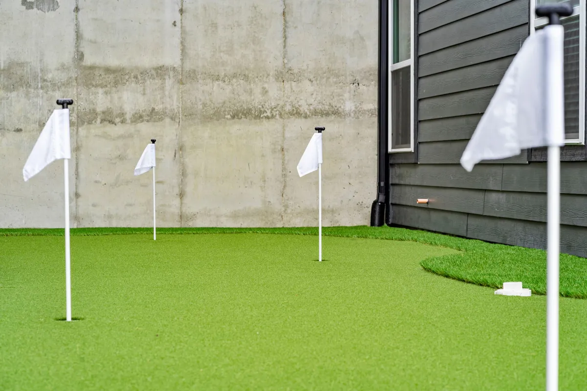 This image captures a private putting green with bright white flags and smooth green turf, set against a backdrop of sunny skies and open space. The setting is inviting and perfect for both solo practice rounds and friendly group matches.