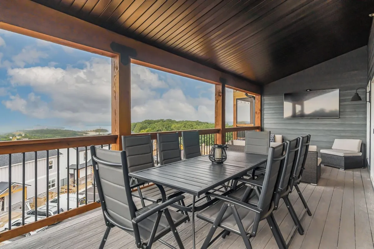 This image captures an outdoor dining table and lounge area set against a scenic lake view. The setup features comfortable seating for groups, perfect for alfresco dining or relaxing while watching a game outdoors. The atmosphere feels inviting and social, with plenty of space for gatherings.